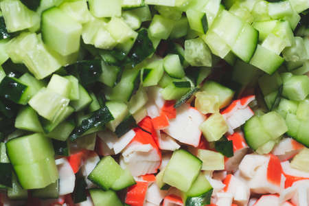 Chopped crab sticks and cucumber pieces close up. Salad ingredients. Vegetable backgroundの写真素材