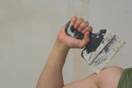 Hand holds construction spatula with putty. trowel with spackling. process of renovationの写真素材