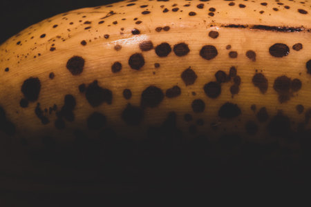 Overripe yellow banana with black spots close up