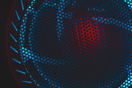 Colorful light of computer fan shines through the holes of protective grid. illumination glows in the dark. abstract futuristic background. led lighting of gaming pcの写真素材