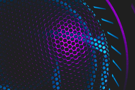 Colorful light of computer fan shines through the holes of protective grid. illumination glows in...