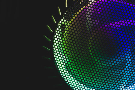 Colorful led lights of computer fan shines through the protective grid. illumination glows in the dark. abstract futuristic backgroundの写真素材