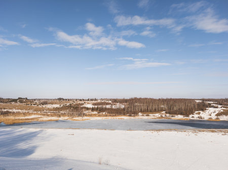 Frozen river landscape with forest on a sunny dayの写真素材