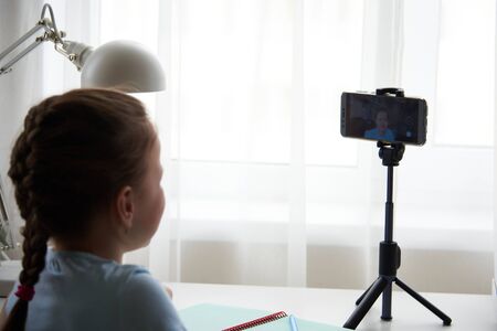 a beautiful cute little girl blogger records videos on her smartphone for her subscribers.の写真素材