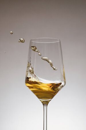 glass of white wine with wave on white and blue backgroundの写真素材