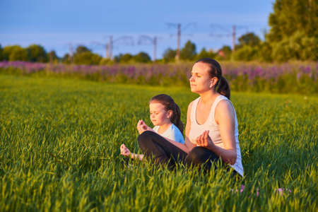 a mother and her child do yoga in the fresh air. The concept of a healthy lifestyle. Outdoor recreation. Meditation and yoga classesの写真素材