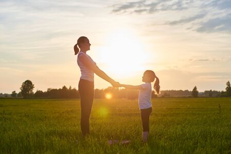 a mother and her child do yoga in the fresh air. The concept of a healthy lifestyle. Outdoor recreation. Meditation and yoga classesの写真素材
