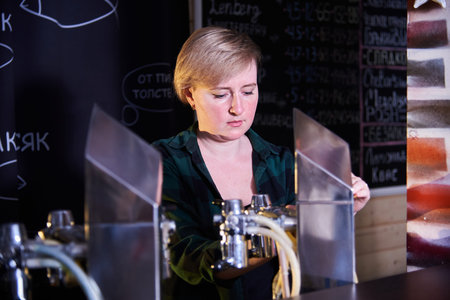 a young woman pours beer at the draught beer bar.Malt drink for international beer day