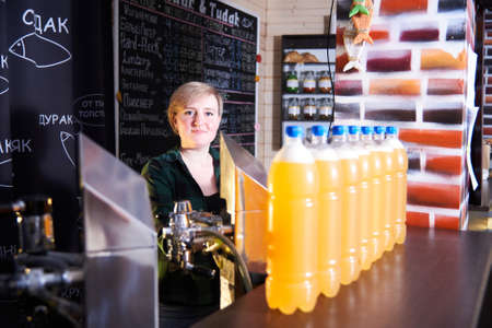 a young woman pours beer at the draught beer bar.Malt drink for international beer dayの写真素材