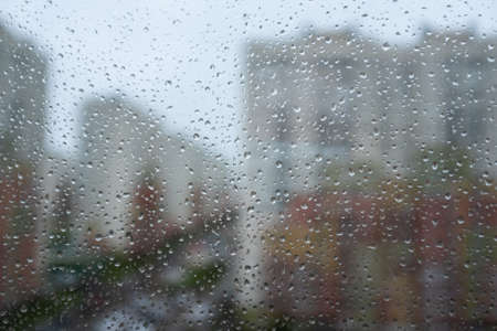 raindrops on the glass. A modern residential complex is visible in the focusの写真素材