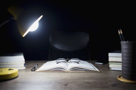 Reading table at night, Open books and glasses placed, Book Division and lighting lamps, Close-up on glasses.の写真素材