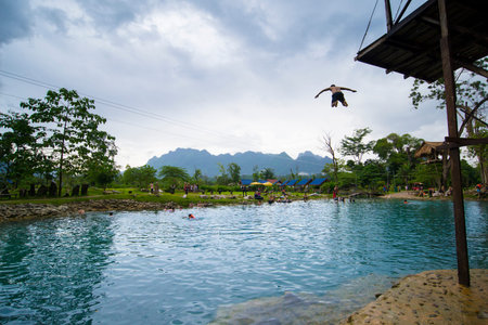 BLUE LAGOON, VANG VIENG, LAOS - JULY 26, 2019: Tourists are jumping into the water from high wooden...