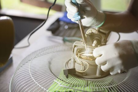 Repair home electrical appliances, Technician is repairing the fan on the desk. Close-up, Copy-spaceの写真素材
