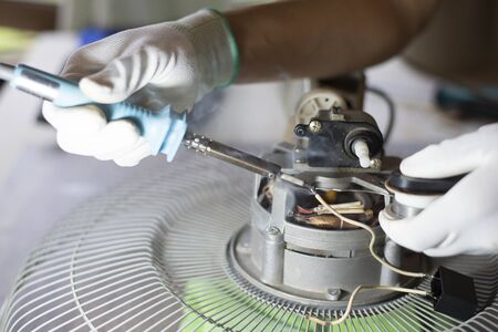 Repair home electrical appliances, Technician is repairing the fan on the desk. Close-up, Copy-spaceの写真素材