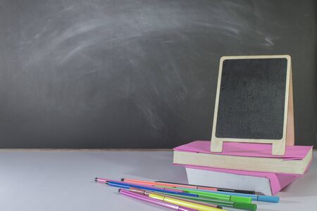 Stationery, books, mini blackboard placed on table in classroom, Blackboard as a backdrop, Close-up, Copy-spaceの写真素材