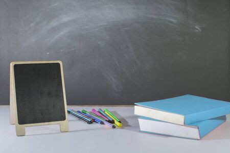 Stationery, books, mini blackboard placed on table in classroom, Blackboard as a backdrop, Close-up, Copy-spaceの写真素材