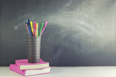 Books stack and Stationery placed on table in classroom, Blackboard wall, Back to school concept.の写真素材