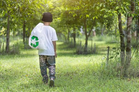 One child walks with garbage bags, Among the green forest, Caring for the environment, Copy-spaceの写真素材