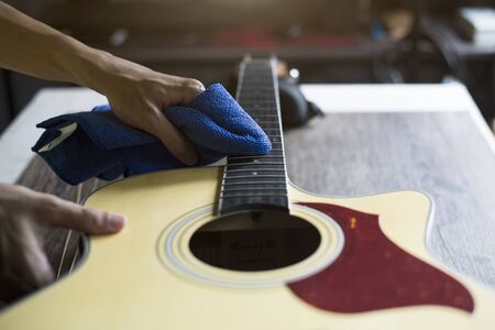 Guitar repairer is cleaning acoustic guitar, Clean cloth to wipe the fretboard, Close-upの写真素材