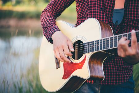 Music in nature, Man playing an acoustic guitar in meadow, Close-up, Copy-spaceの写真素材
