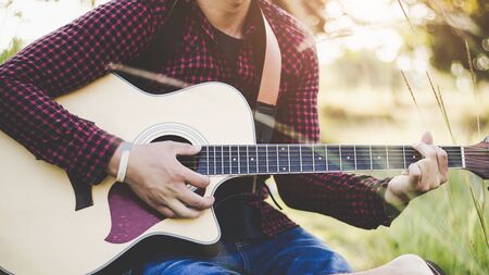 Music in nature, People playing guitar in rural grasslands, Close-upの写真素材
