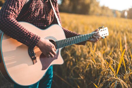 Country music, Man playing acoustic guitar in rice field, Focus on guitar stringsの写真素材
