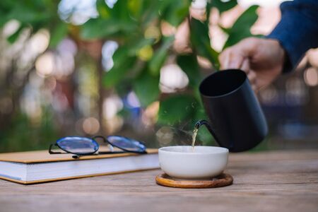 Garden reading table, Hand is pouring tea into the teacup, Close-upの写真素材