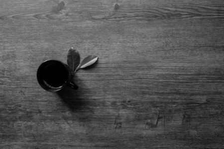 Coffee cup and leaves on the table, Black and white minimal concept, Close-up, Copy-space.の写真素材