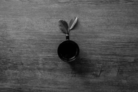 Coffee cup and leaves on the table, Black and white minimal concept, Close-up, Copy-space.の写真素材
