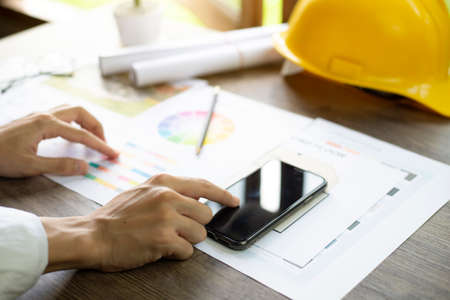 Architect's desk, Architects are comparing designs in smartphone, Close up at hand.の写真素材