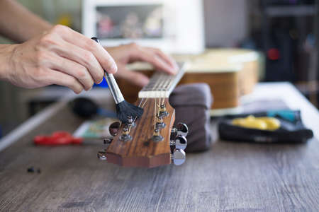Acoustic guitar care, Craftsman is cleaning the guitar with cleaning brush, Close up.の写真素材