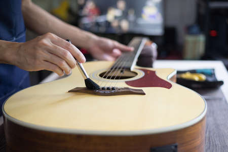 Acoustic guitar care, Craftsman is cleaning the guitar with cleaning brush, Close up.の写真素材