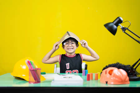 Smiling boy wearing glasses, Take a book on top of the head, Learning materials on the table.の写真素材