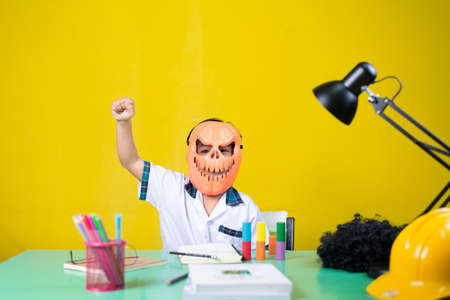 Child wearing a devil mask, Look happy, Homework desk.の写真素材