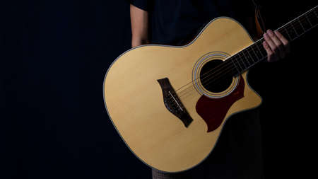Musician with an acoustic guitar in the dark, At night with side lighting, Copy space.の写真素材