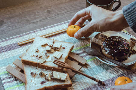 Breakfast arrangement, People putting orange on the table, Focus on orange and hand, Copy space.の写真素材