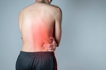 Back muscle injury, Man standing with his hands on his waist, Copy space.