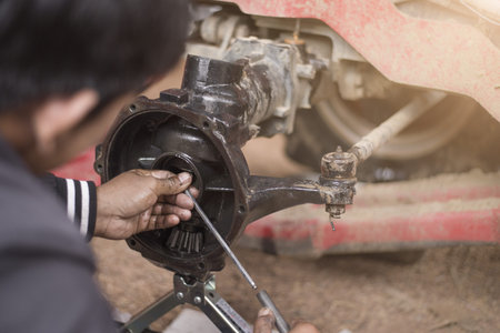 Mechanic repairing tractor axle, close to axle.
