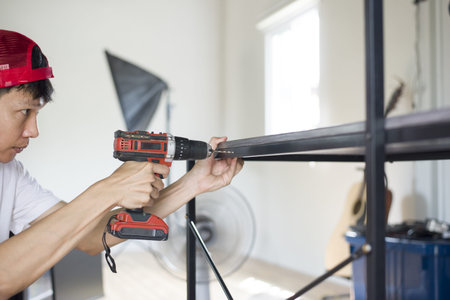 Asian man drilling table with cordless drill, Close up and copy space.