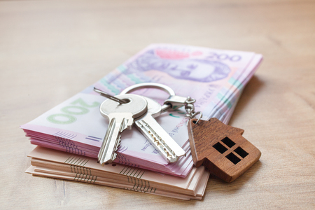 Real estate investing concept. Ukrainian hryvnia, cash or housing. Keys close upの写真素材