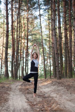 Woman practicing yoga alone in the forest outdoor. Morning summer meditationの写真素材
