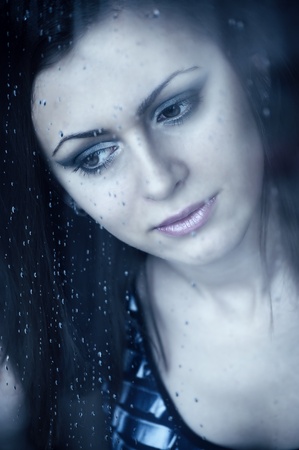 Young girl watching through the window, after a rain. Portrait.の写真素材