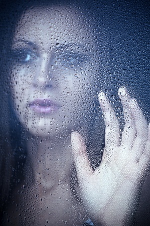 a girl watching through the window after a rain. Portrait.の写真素材