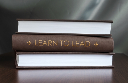 Books on a table and one with "Learn to lead" cover. Book concept.の写真素材