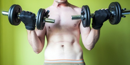 young  man exercising with dumbbells to lose weightの写真素材
