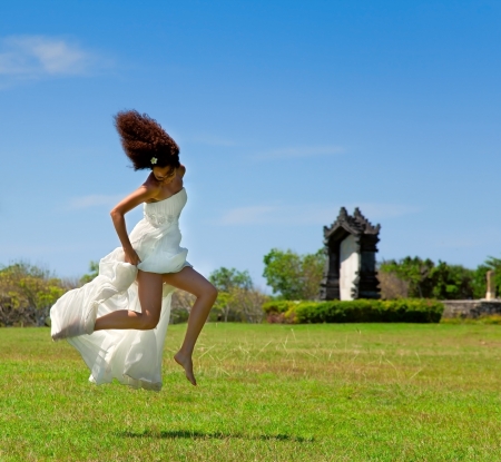 Bride jumped up on a sunny day on the green grassの写真素材