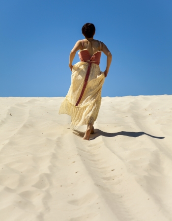 Silhouette of lonely young woman walking on sand in desertの写真素材
