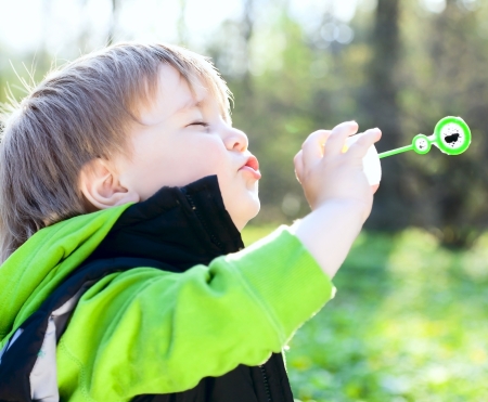 Portrait of funny little boy blowing soap bubblesの写真素材