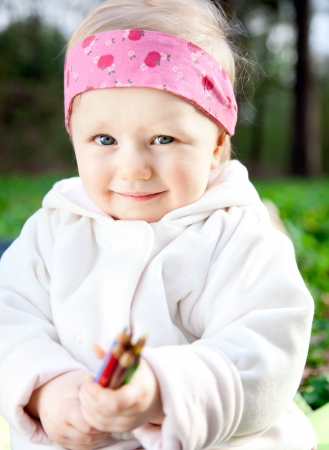 Beautiful sweet girl in the park with colored pencils in handの写真素材