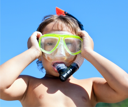 Boy in mask with a tube for diving on blue bright skyの写真素材